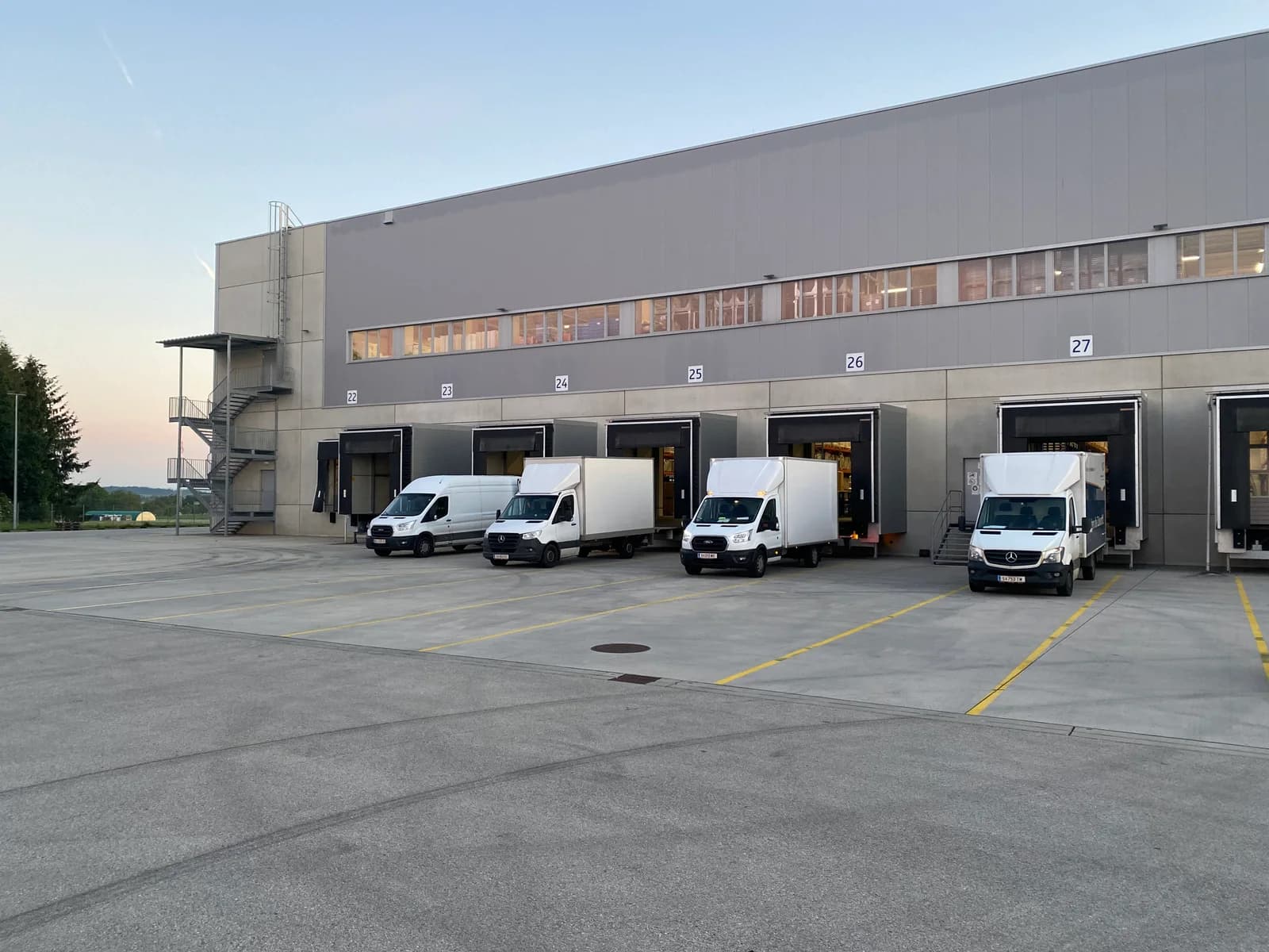 Mehrere Transportfahrzeuge vor den Ladetoren einer Halle